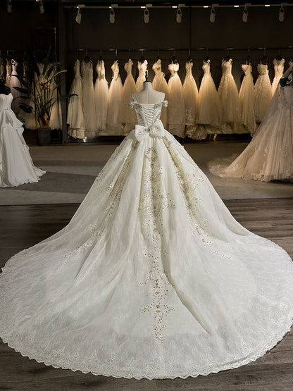 Superbes robes de mariée en robe de bal avec traîne chapelle et épaules dénudées avec des appliques de nœud papillon et de perles