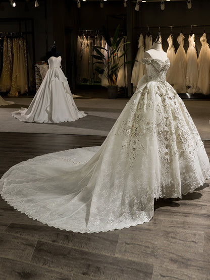 Superbes robes de mariée en robe de bal avec traîne chapelle et épaules dénudées avec des appliques de nœud papillon et de perles